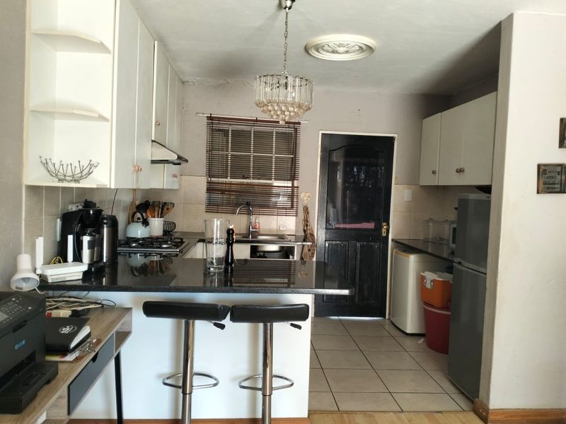 A functional kitchen featuring granite countertops, built-in cabinetry, a gas hob, and tiled flooring, offering a practical layout for daily meal preparation.