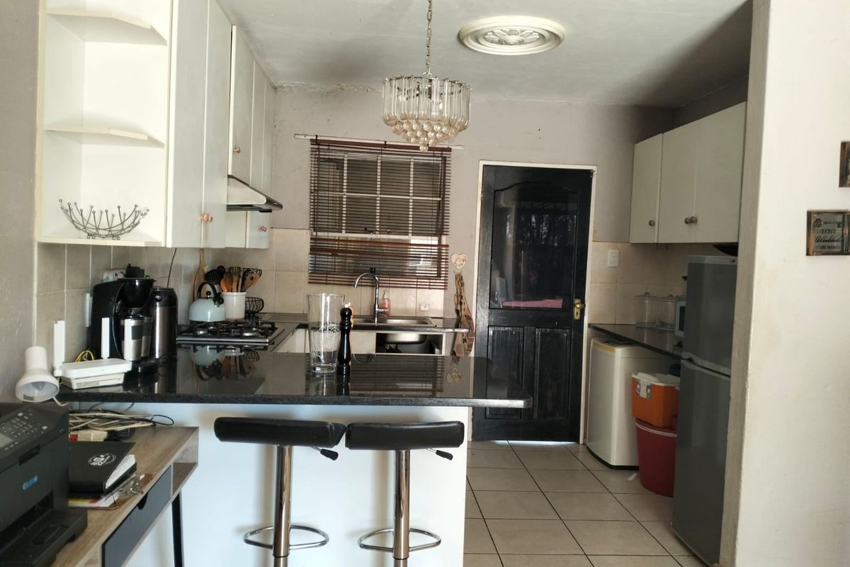 A functional kitchen featuring granite countertops, built-in cabinetry, a gas hob, and tiled flooring, offering a practical layout for daily meal preparation.