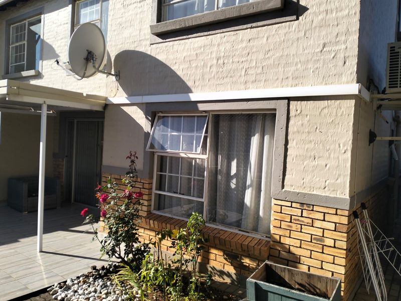 Rear exterior view of the apartment featuring a tiled patio area, brick facade detailing, and an installed satellite dish.