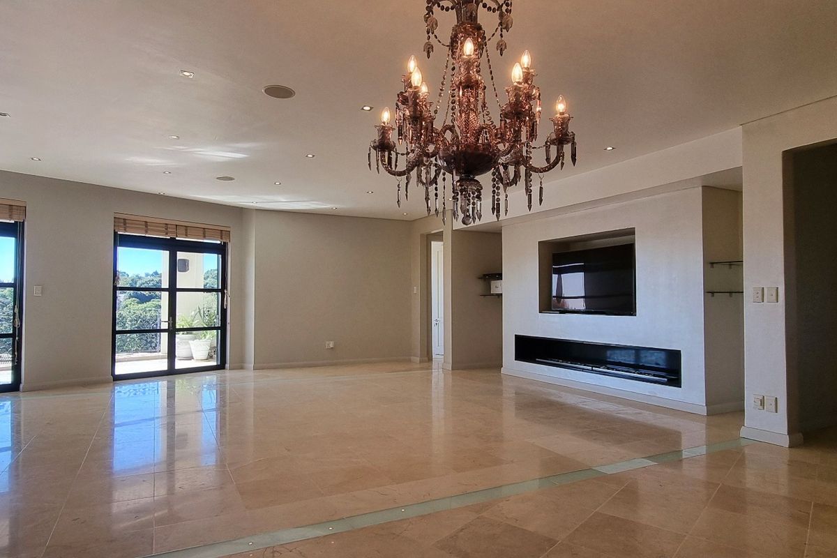 Spacious open-plan living area featuring polished marble flooring, a modern built-in fireplace, recessed lighting, and large sliding doors leading to an outdoor balcony.