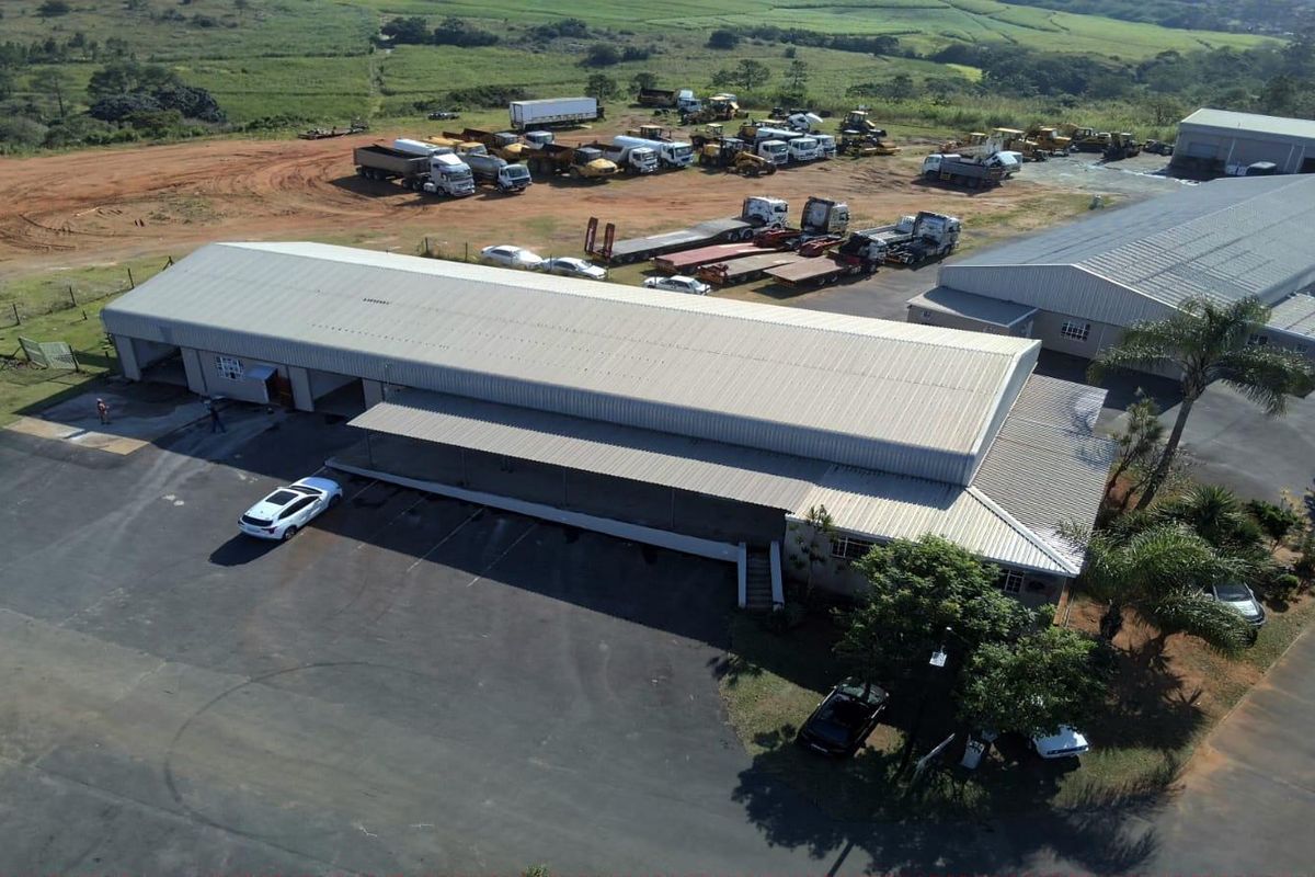 Aerial view of an industrial property featuring a large warehouse building, extensive asphalt parking, and a dedicated loading bay area.
