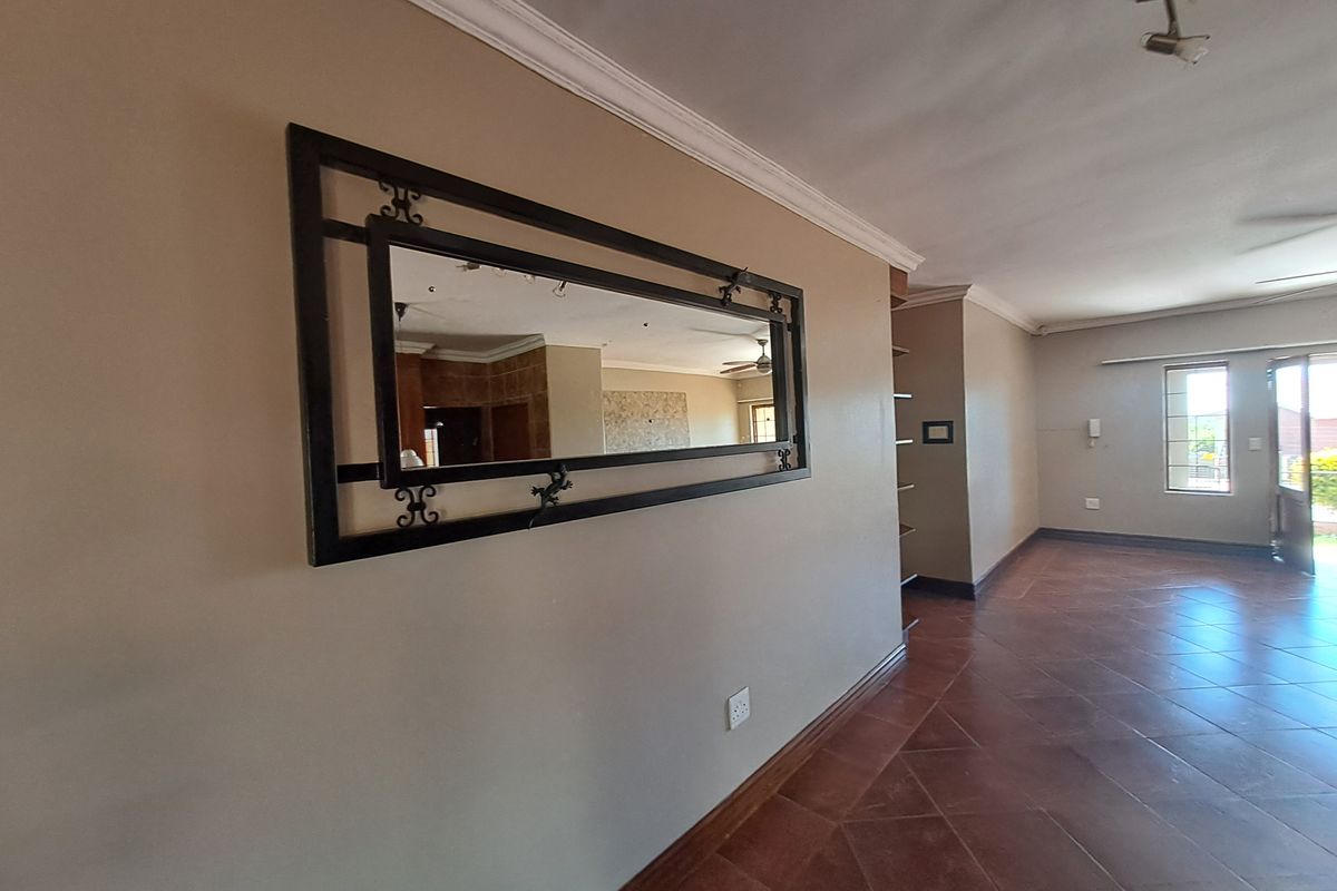 Spacious living area featuring tiled flooring, crown molding, and built-in shelving, offering a neutral canvas for interior design.