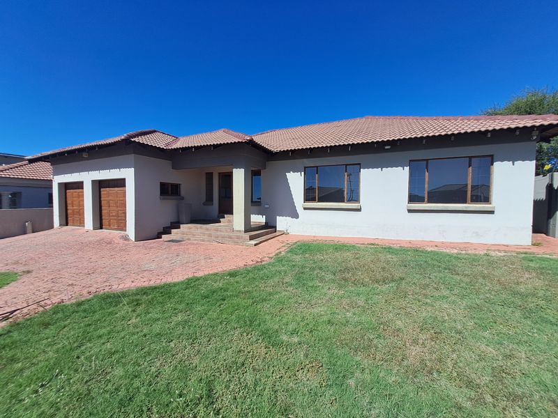 Front elevation of a single-story house featuring a double garage, paved driveway, tiled roof, and a covered entrance porch.