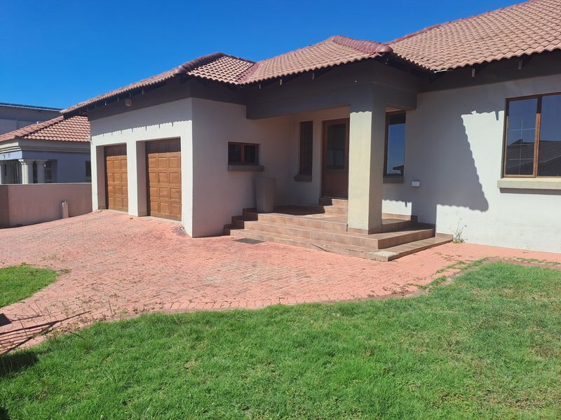 Front elevation of a single-story house featuring a double garage, paved driveway, and a covered entrance porch with tiled steps.
