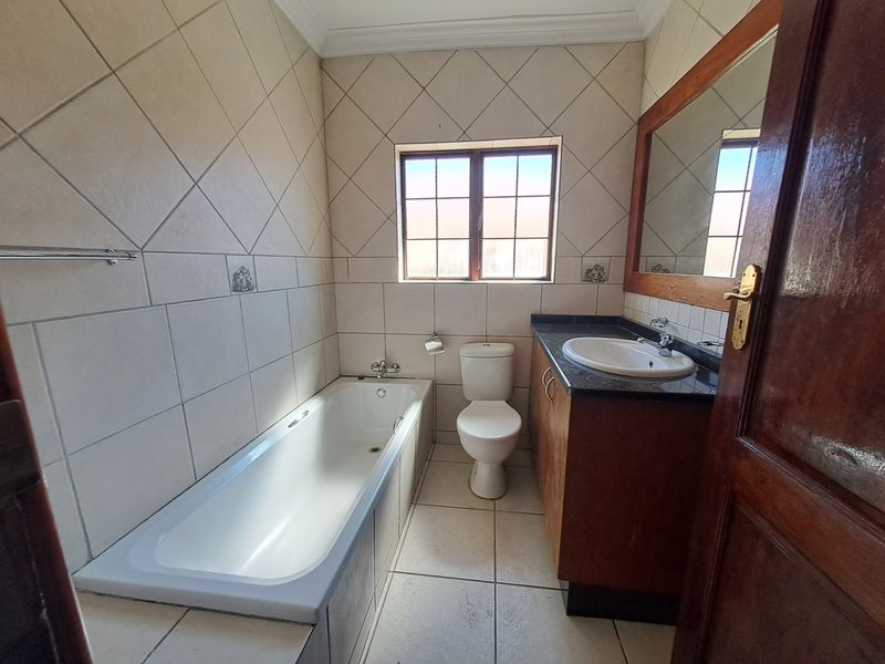 A functional bathroom featuring a built-in vanity with granite countertop, a bathtub, and tiled finishes throughout.