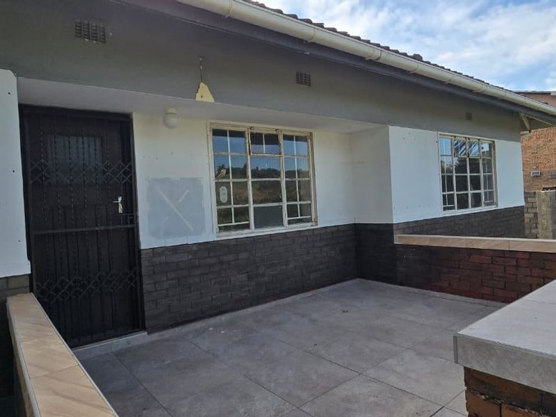 A covered patio area featuring tiled flooring and brick accents, currently requiring minor cosmetic repairs and finishing touches to the exterior walls.