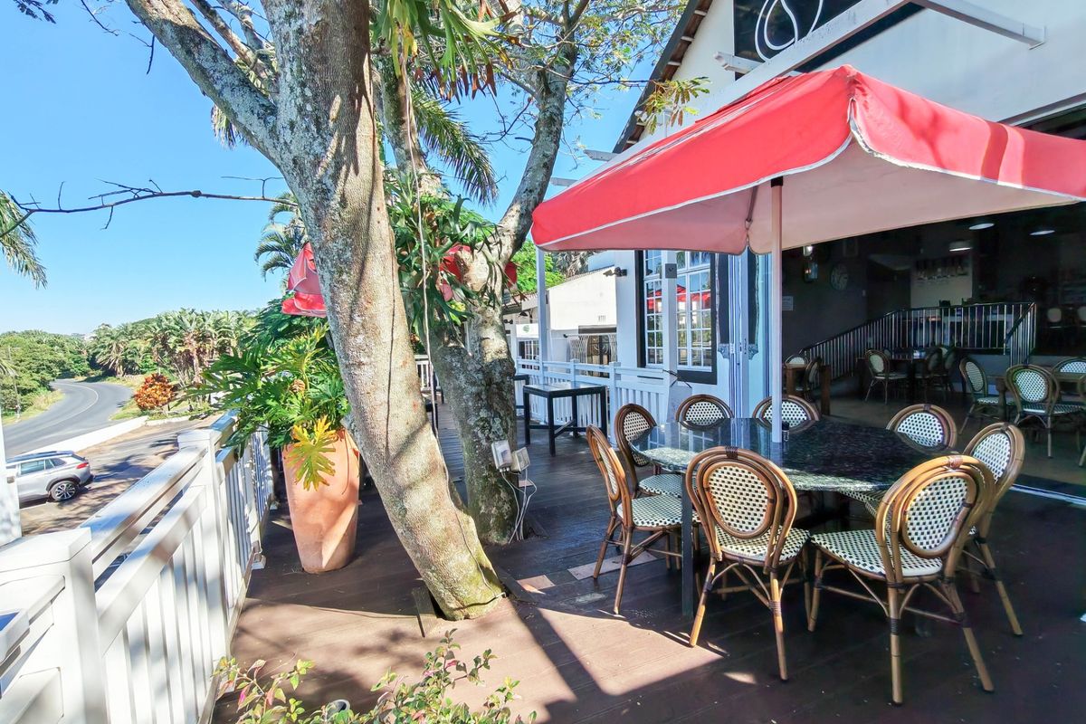 A spacious outdoor timber deck patio area featuring integrated railing and mature trees, providing an inviting space for commercial dining or relaxation.