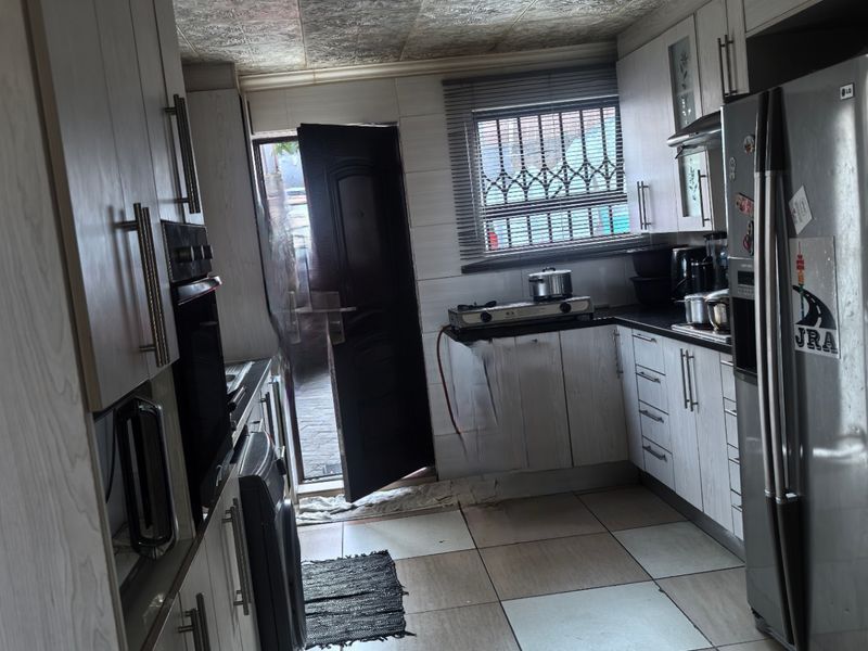 A functional kitchen featuring light wood-grain cabinetry, tiled flooring, a built-in oven, and direct access to an outdoor area.