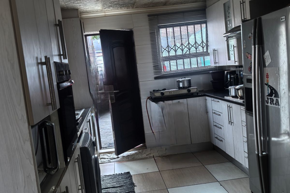A functional kitchen featuring light wood-grain cabinetry, tiled flooring, a built-in oven, and direct access to an outdoor area.