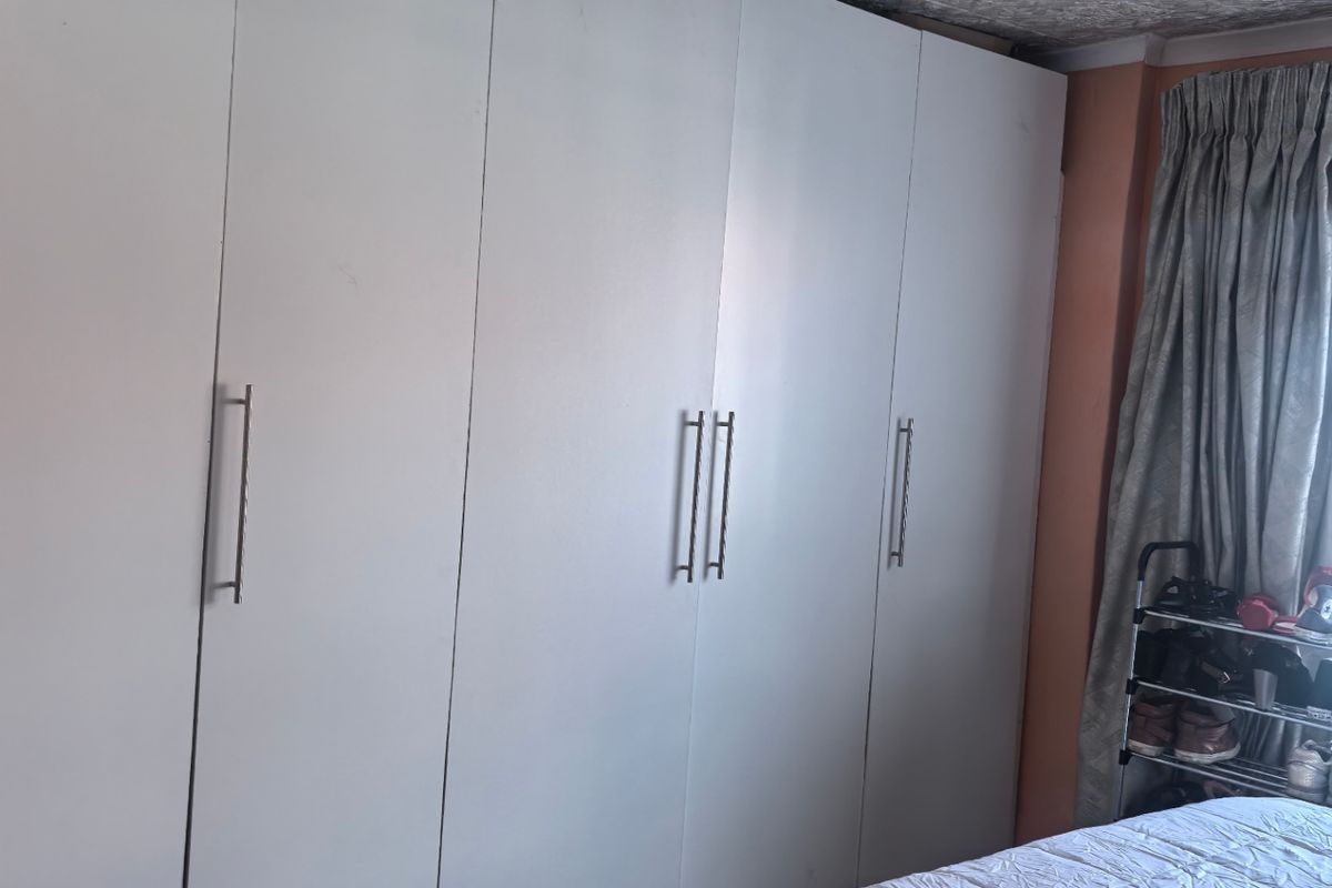 Bedroom featuring floor-to-ceiling built-in wardrobes with white cabinetry and tiled flooring.