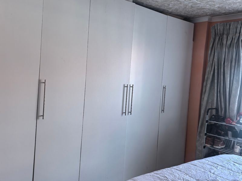 Bedroom featuring floor-to-ceiling built-in wardrobes with white cabinetry and tiled flooring.
