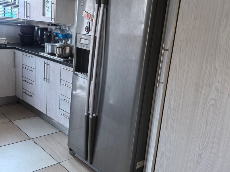 A functional kitchen featuring light wood-grain cabinetry, dark countertops, tiled flooring, and a built-in extractor fan.