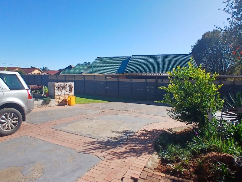 A view of the front exterior featuring a paved driveway, perimeter wall, and tiled roof structure.