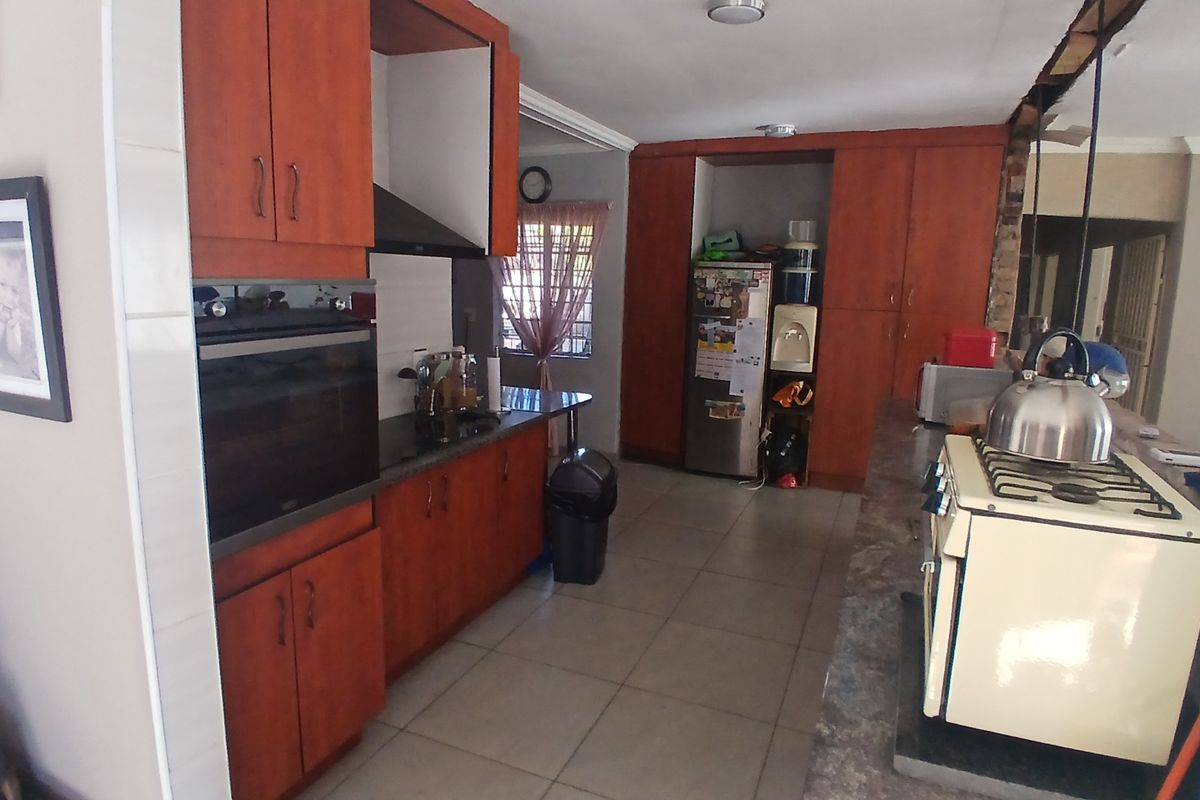A dated kitchen featuring wood-tone cabinetry, stone countertops, and tiled flooring, requiring cosmetic updates to modernize the space.