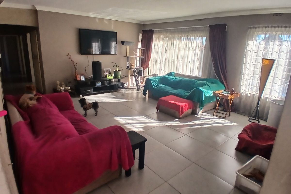 Spacious living room featuring large windows, tiled flooring, and coved ceiling details, offering a bright and open layout for comfortable family living.