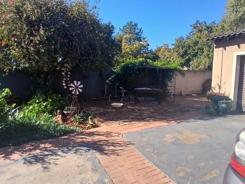 A rear garden area featuring brick paving, a boundary wall, and access to the garage, providing a functional outdoor space.