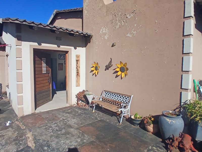 Front entrance area featuring a timber door, tiled roof, and stone paved patio, showing signs of exterior wall paint deterioration.