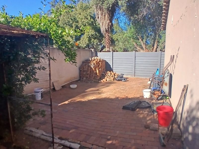 A rear outdoor area featuring brick paving and boundary walls, offering potential for landscaping or a private patio space.