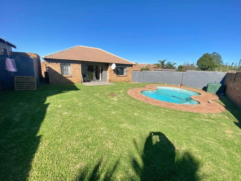 Rear view of the property featuring a private garden, a swimming pool with brick surround, and a tiled roof structure.