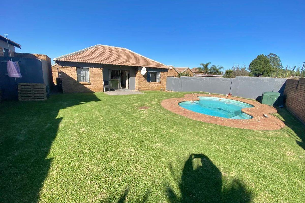 Rear view of the property featuring a private garden, a swimming pool with brick surround, and a tiled roof structure.