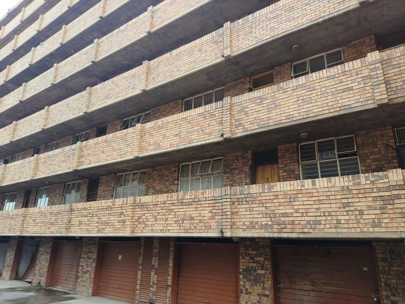 Exterior view of a multi-story apartment building featuring face brick construction, private balconies, and ground-level garage access.