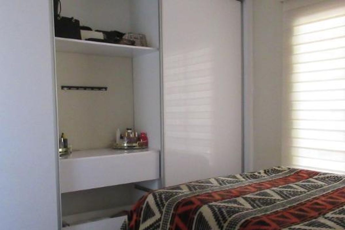 A bedroom featuring a built-in wardrobe with integrated shelving and modern roller blinds for light control.
