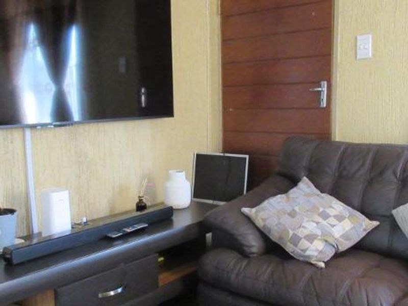 A living room area featuring textured wall finishes and a wooden door, providing a functional space for relaxation.