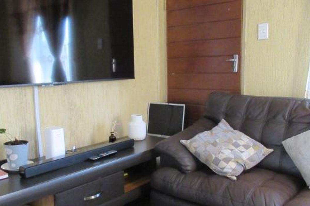 A living room area featuring textured wall finishes and a wooden door, providing a functional space for relaxation.
