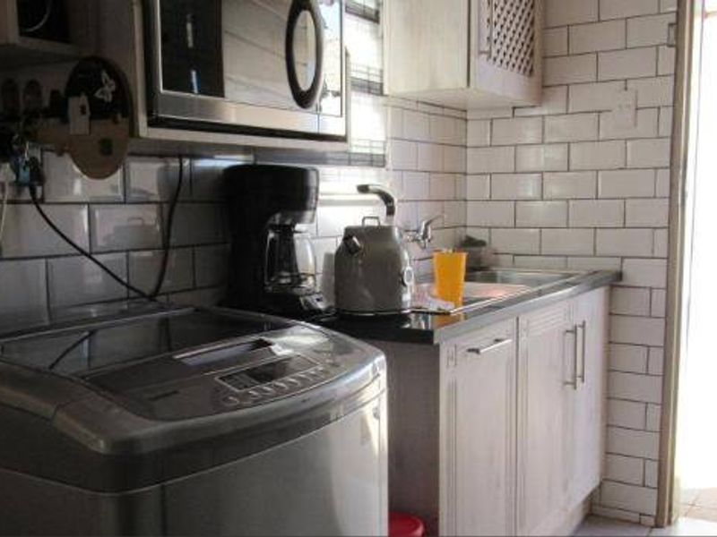 A functional laundry area featuring subway tile backsplash, built-in cabinetry, and a stainless steel sink with direct access to the exterior.