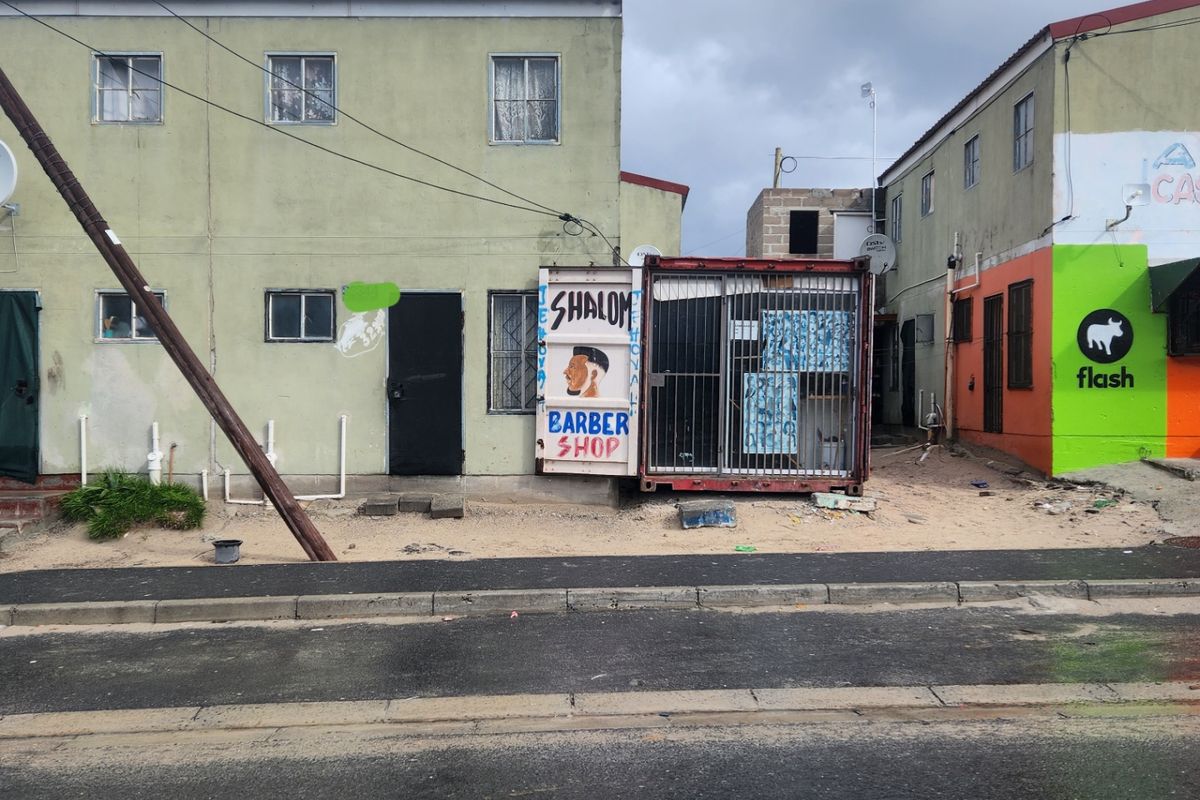Street-level view of a multi-story residential building featuring a makeshift commercial container structure attached to the front facade.