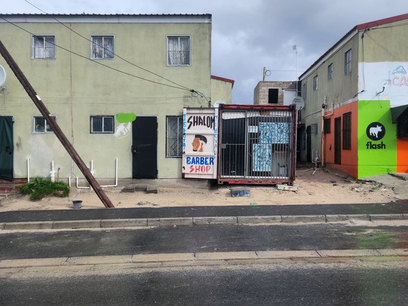 Street-level view of a multi-story residential building featuring a makeshift commercial container structure attached to the front facade.