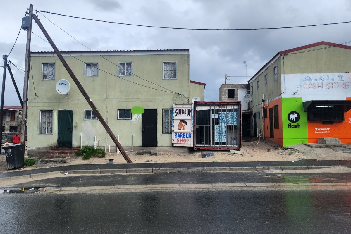 Street-level view of a multi-unit residential and commercial building featuring a mix of residential living spaces and ground-floor shopfronts.