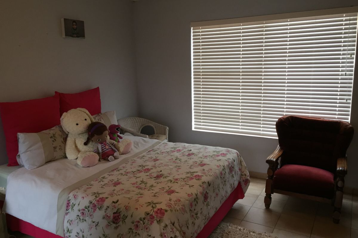 A bedroom featuring tiled flooring and venetian blinds, providing a functional space with neutral wall finishes.