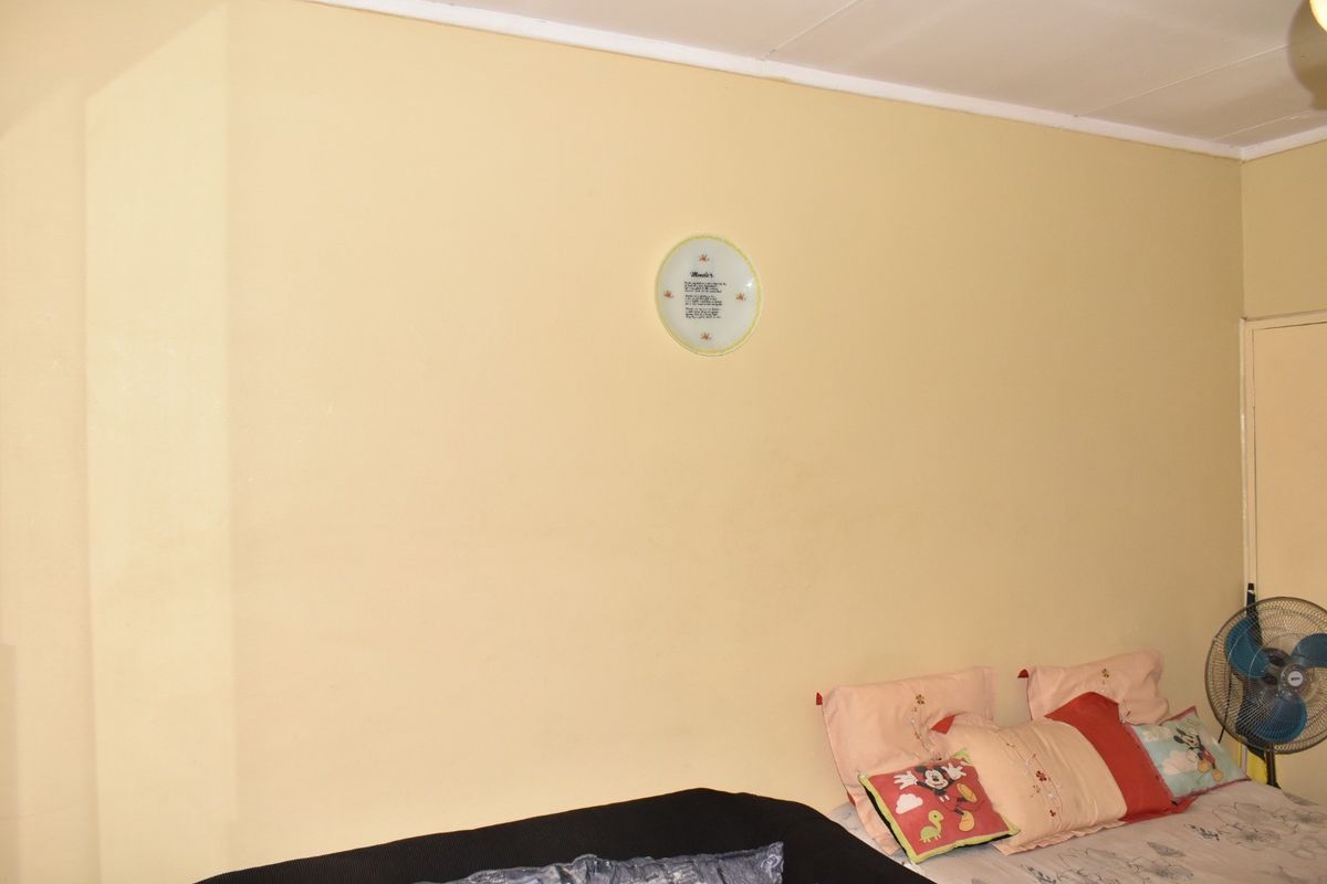A bedroom interior featuring plain yellow walls and a standard ceiling finish.