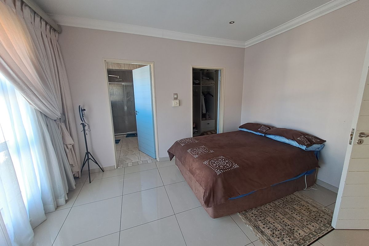 Spacious bedroom featuring tiled flooring, recessed ceiling lighting, en-suite bathroom access, and a walk-in closet area.