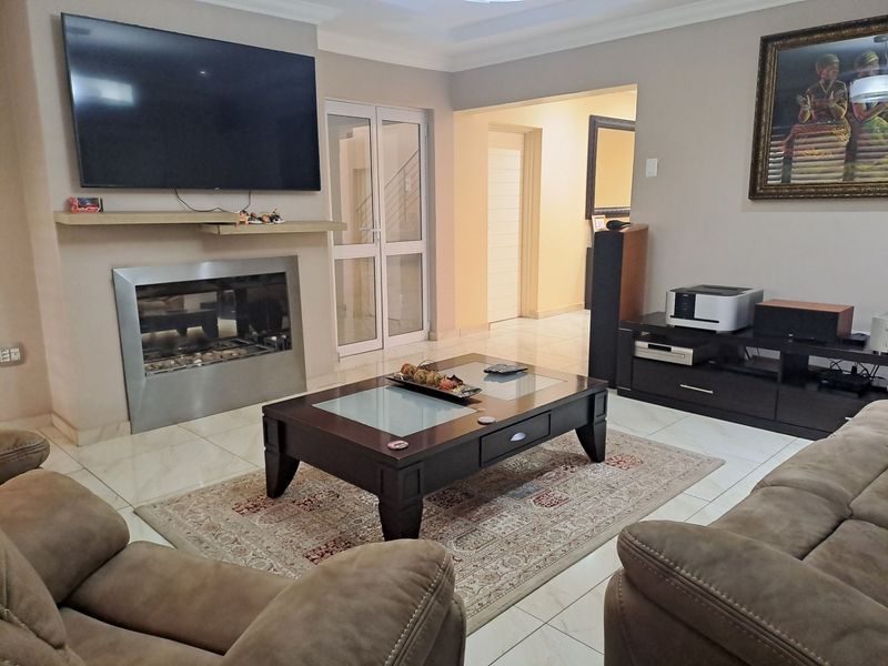 A comfortable living room featuring a modern built-in fireplace, tiled flooring, and neutral wall tones, providing a functional and inviting space.