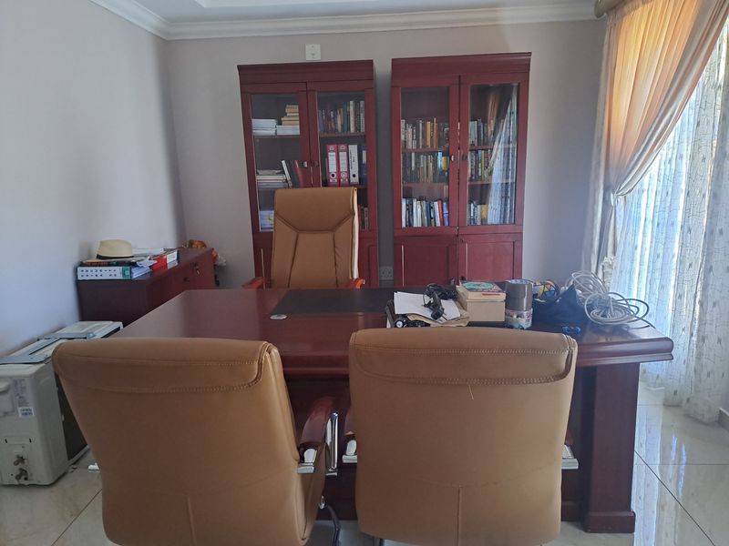 A home office space featuring tiled flooring, crown molding, and access to a sliding glass door, providing a functional workspace.