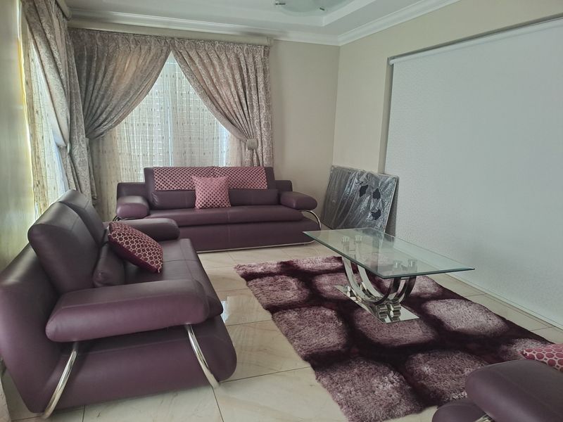 A spacious living room featuring polished tiled flooring and a recessed ceiling design, providing a neutral base for interior styling.