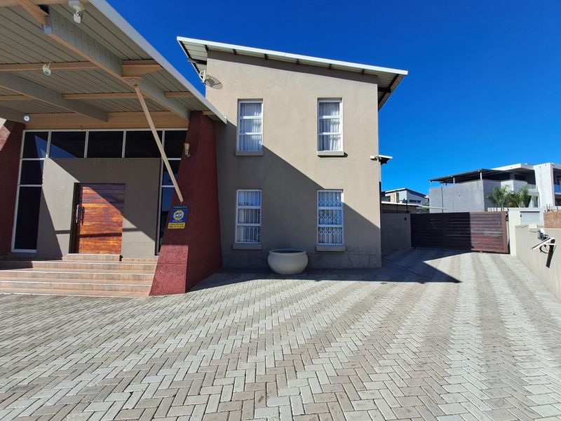 Front elevation of a modern two-story house featuring a paved driveway, tiled entrance steps, and a timber front door with security features.