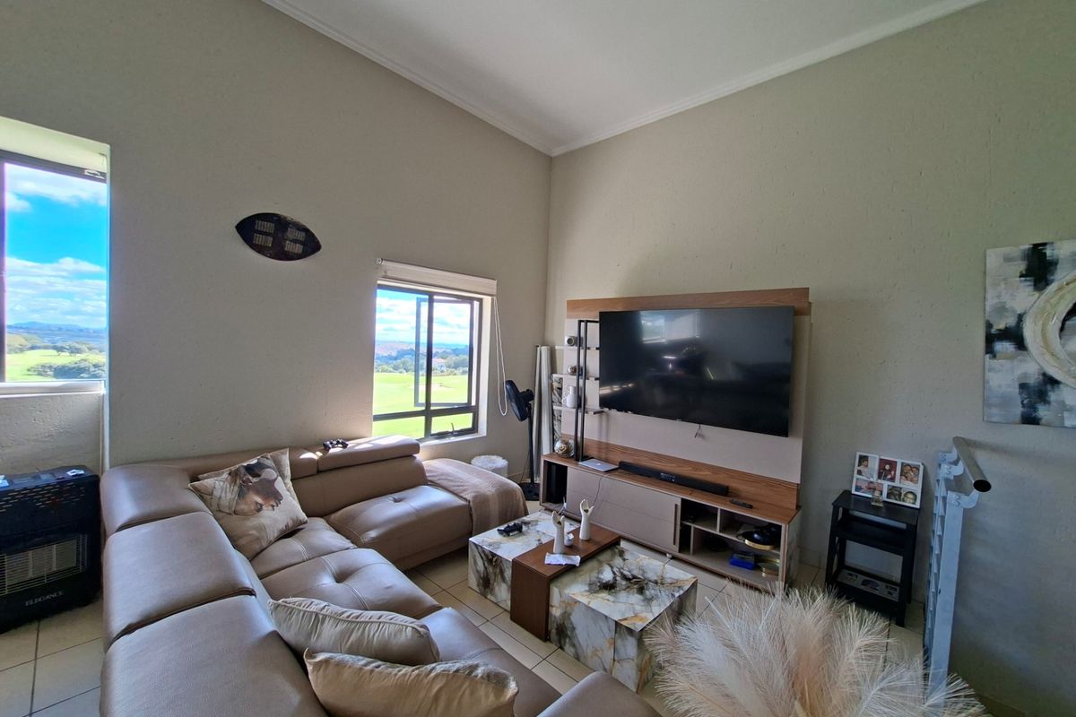 A spacious living room featuring high ceilings, tiled flooring, and large windows that provide natural light and scenic views.