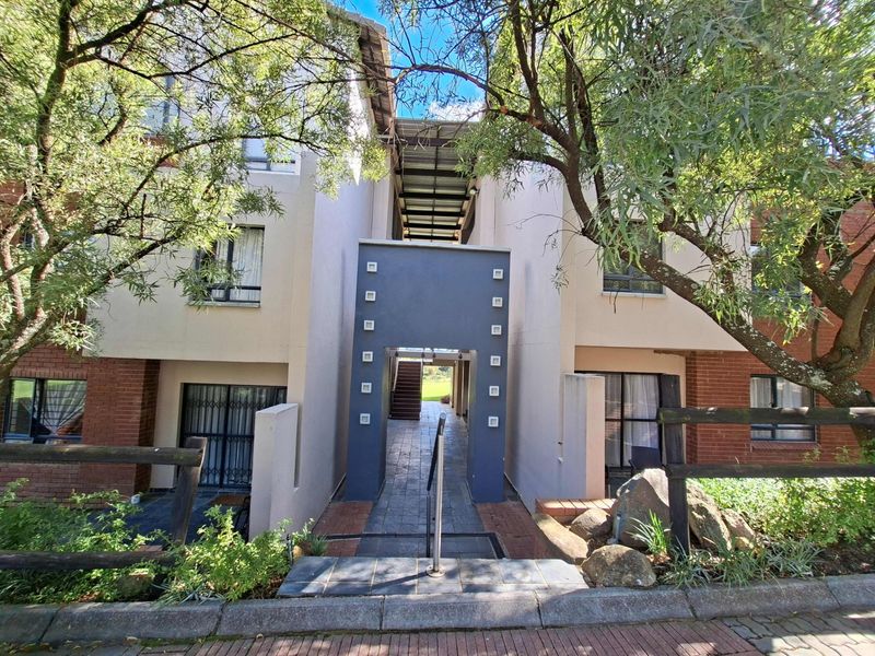 Front exterior view of an apartment complex featuring a paved entrance walkway, brick and rendered facade, and secure access points.