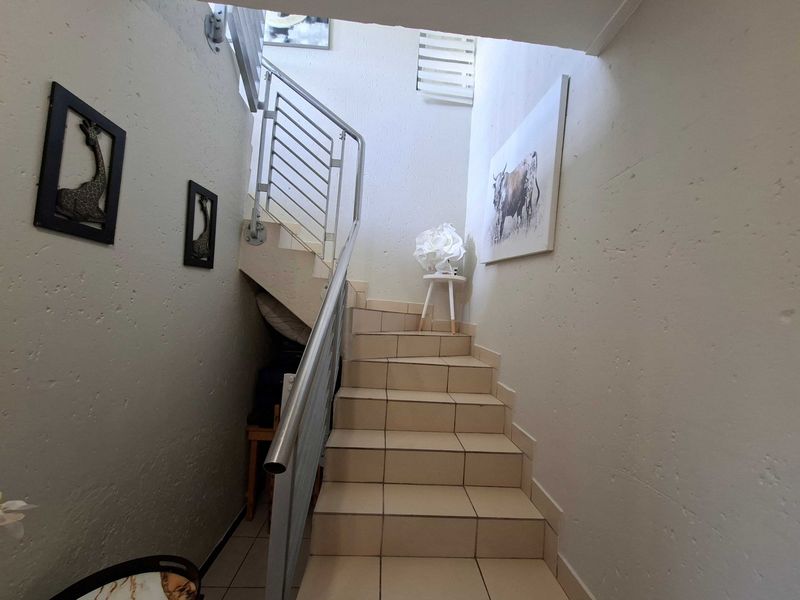A staircase featuring tiled steps and a modern metal handrail, connecting levels within the apartment.
