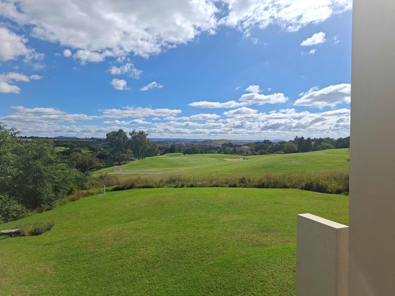 A scenic view overlooking a lush green golf course landscape under a bright blue sky.