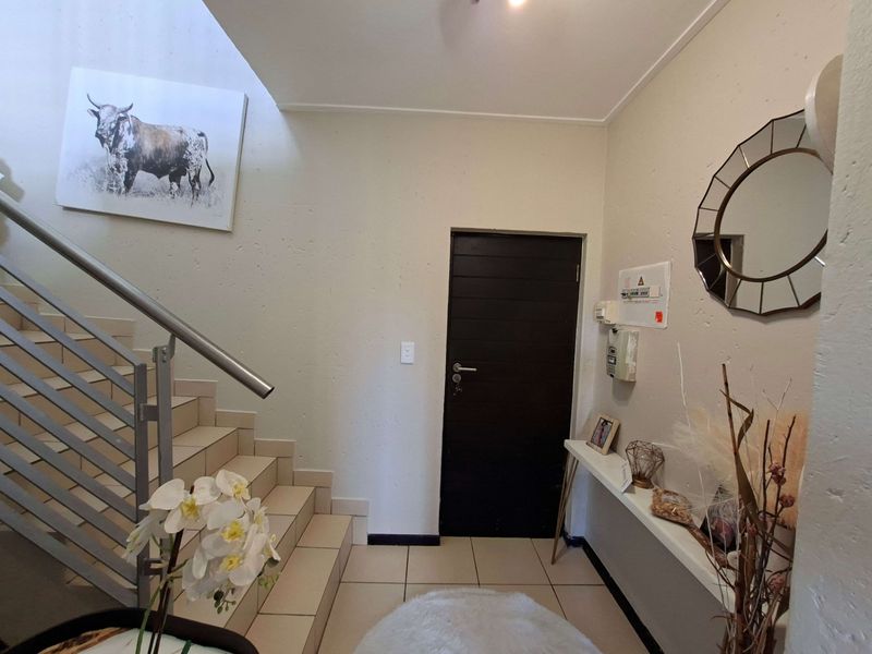 Welcoming apartment entrance featuring a tiled staircase with a modern stainless steel handrail and direct access to the main living area.