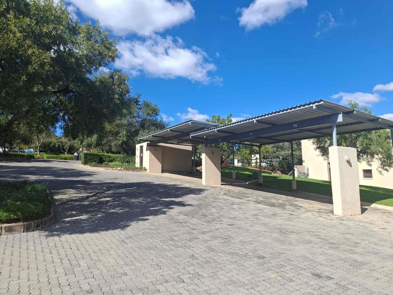 A well-maintained paved driveway featuring a covered carport structure with numbered parking bays and concrete support pillars.