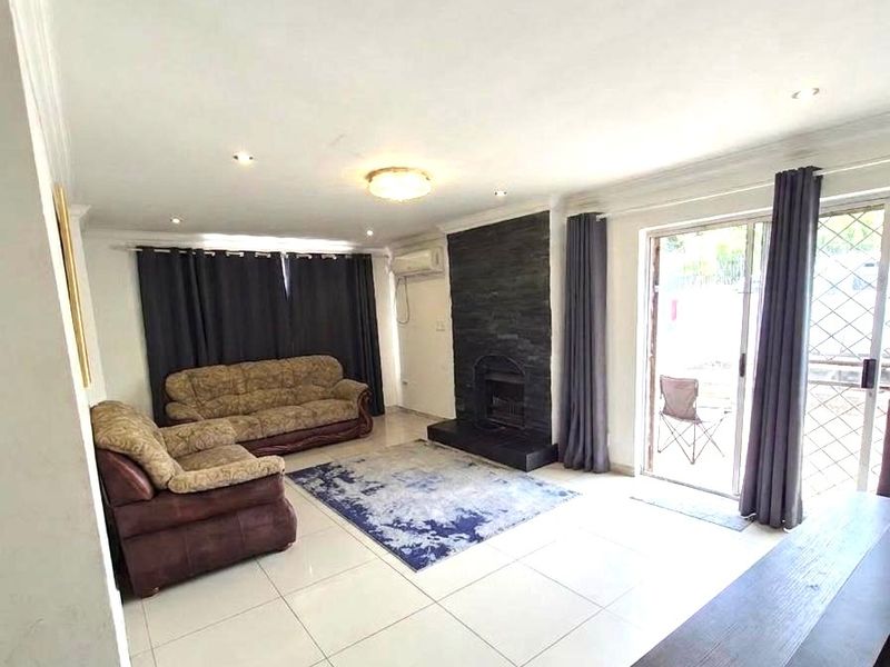 Spacious living room featuring large format floor tiles, a striking black stone feature fireplace, and sliding glass doors providing access to the outdoor area.