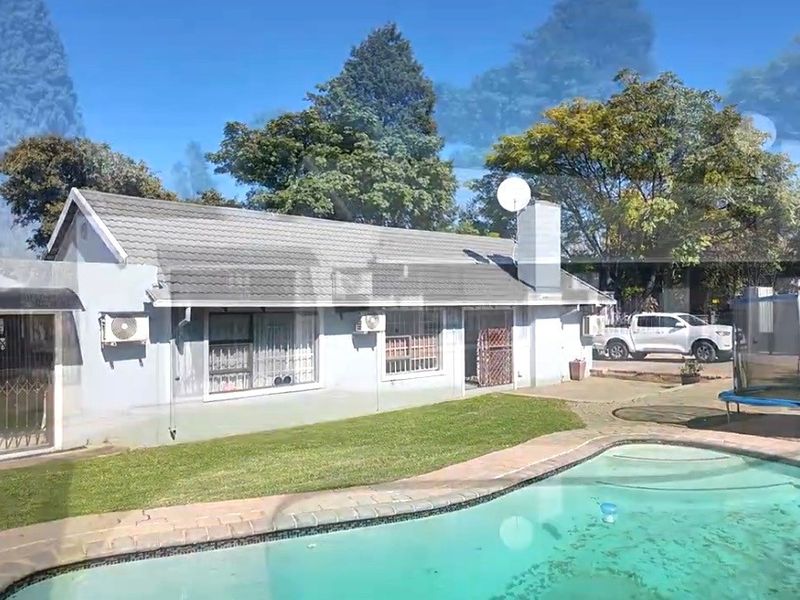Rear view of the house featuring a swimming pool, paved surround, and a well-maintained lawn area.