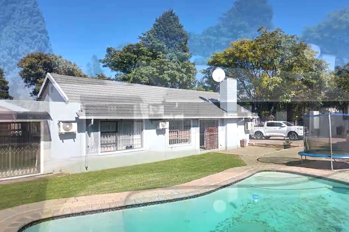 Rear view of the house featuring a swimming pool, paved surround, and a well-maintained lawn area.