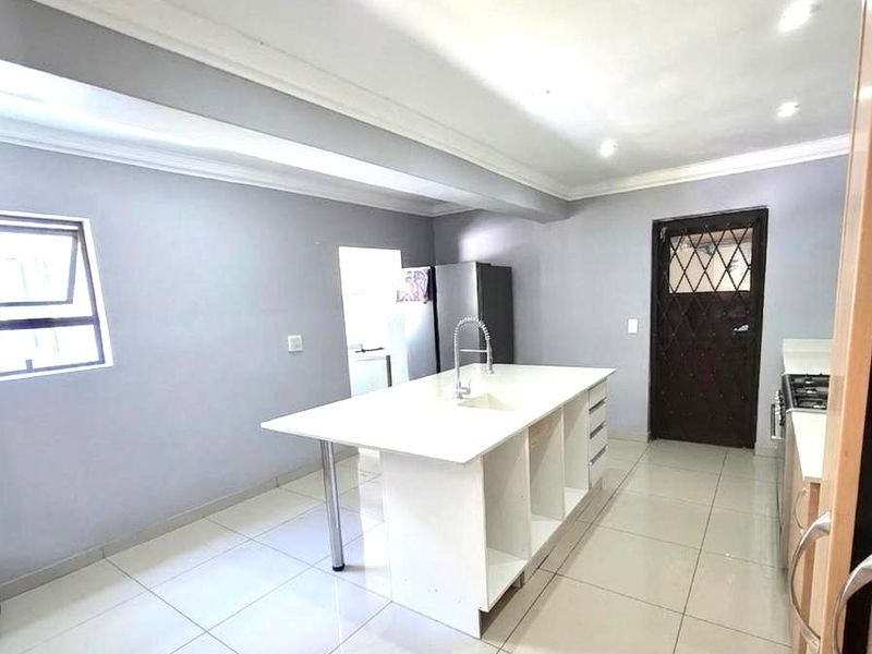 Modern kitchen featuring a central island with a built-in sink, sleek cabinetry, and polished floor tiles.