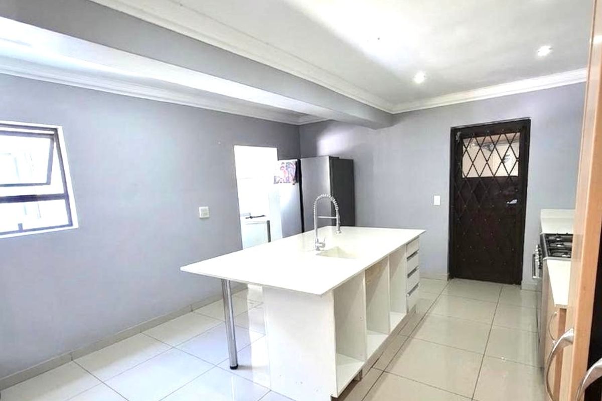 Modern kitchen featuring a central island with a built-in sink, sleek cabinetry, and polished floor tiles.